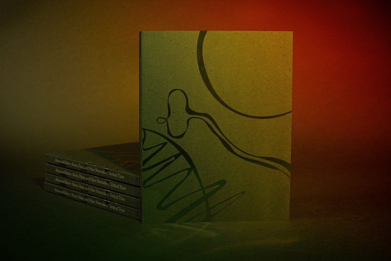 A stack of books with a green cover printed with looping line drawings, lit in green and red.